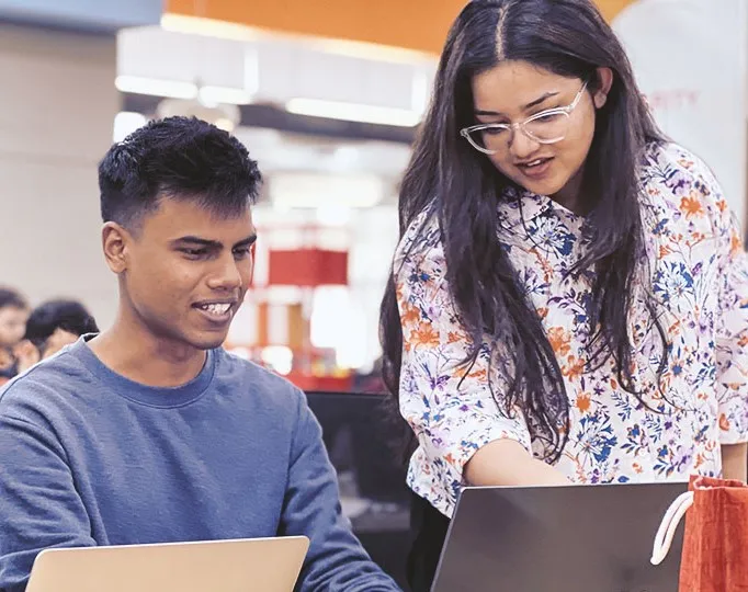 a man and a woman looking at laptops